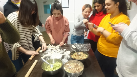 A group of women cooking in a kitchen preparing food

Description automatically generated